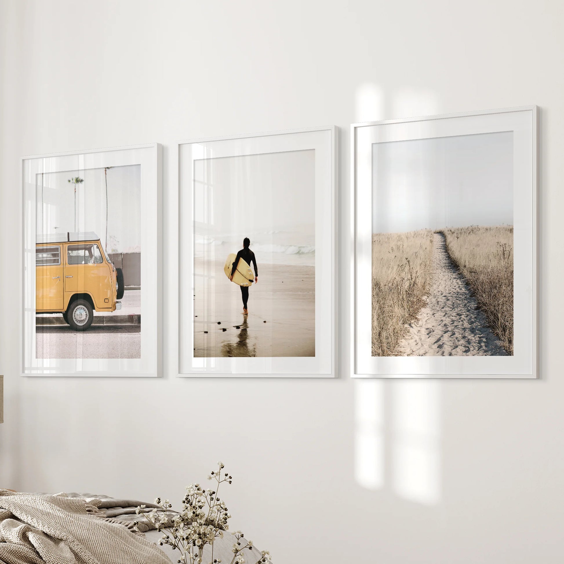 Wall art of three ocean vista prints, matted and framed in white, mounts beside the bed for a light, open feel in the bedroom.