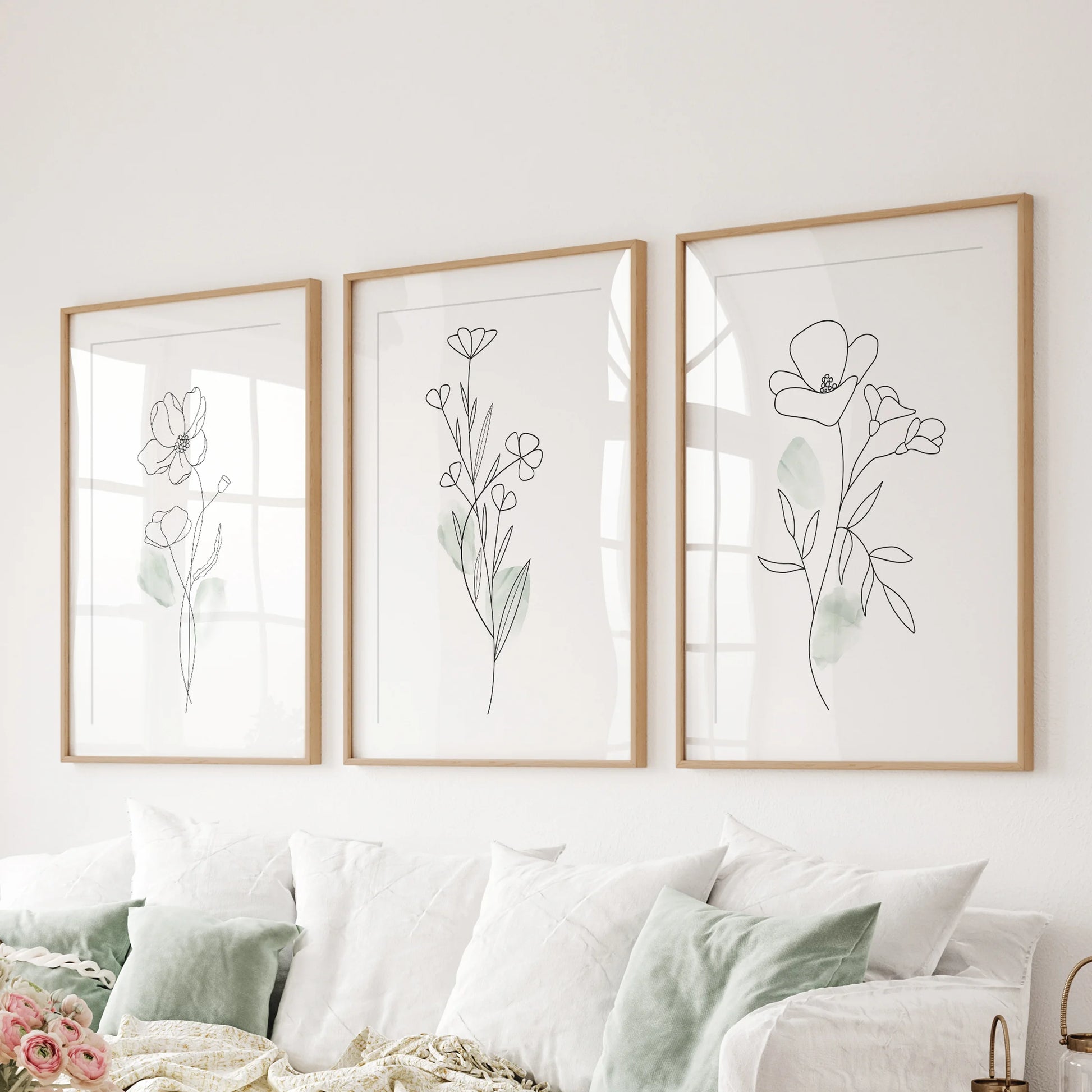 One-line flower drawings in a set of three wall art prints span the sitting room above the couch, wood frames with mats giving the sketches a refined pause.