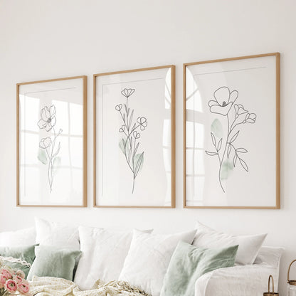 One-line flower drawings in a set of three wall art prints span the sitting room above the couch, wood frames with mats giving the sketches a refined pause.