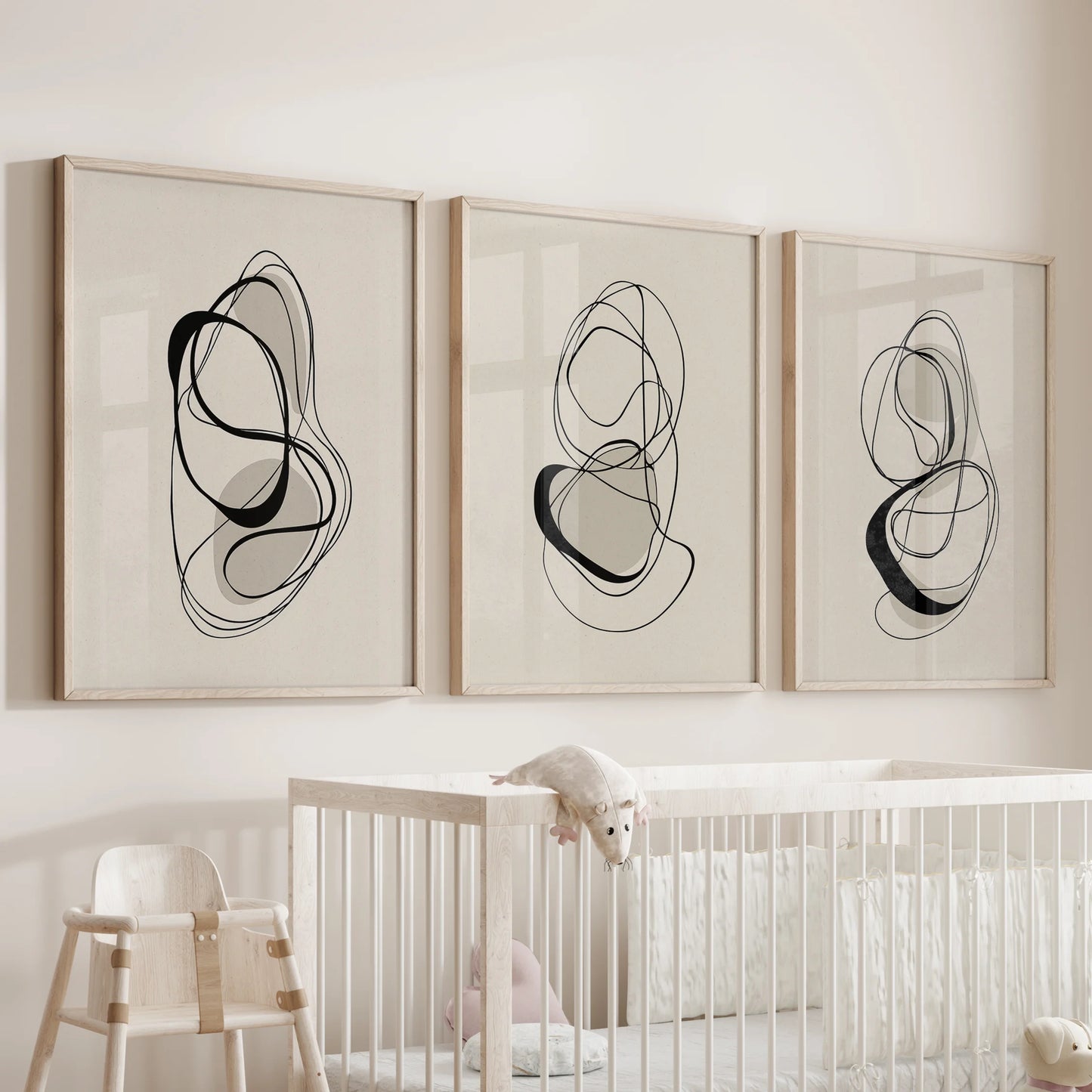Three-print wall set of minimalist line illustrations in oak frames, placed above the bassinet to invite gentle contrast in the baby room.