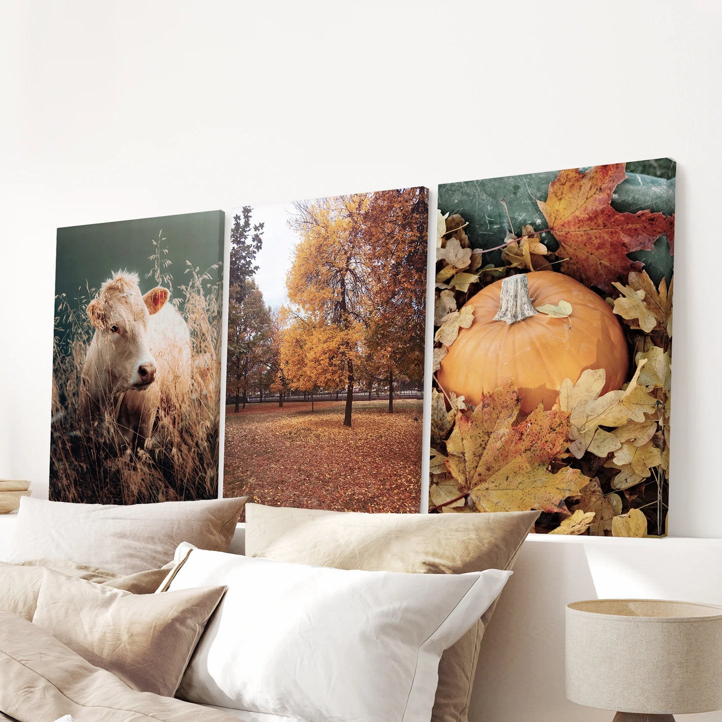 Three wrapped canvas prints of fall foliage stretch cleanly across the wall above the bed headboard for a modern, warm touch.