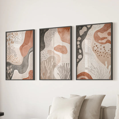 Set of three minimalist prints in slim black frames lines the wall behind the family-room couch, shaping a calm, grounded focal point.