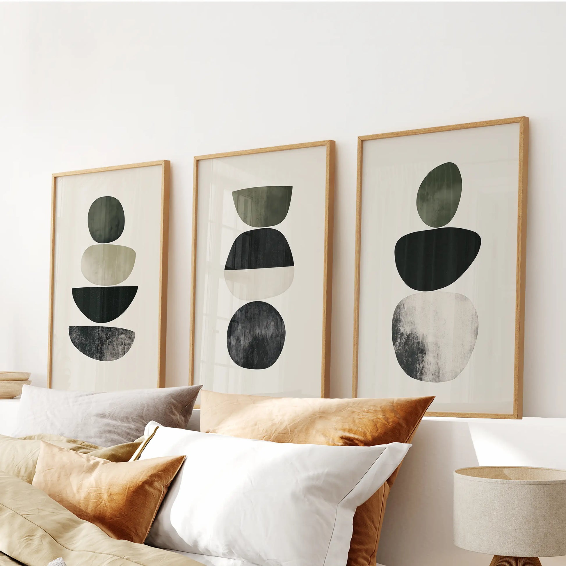A wood-framed trio of Japandi-style abstract prints brings restful balance to the bedroom, aligned neatly above the headboard.