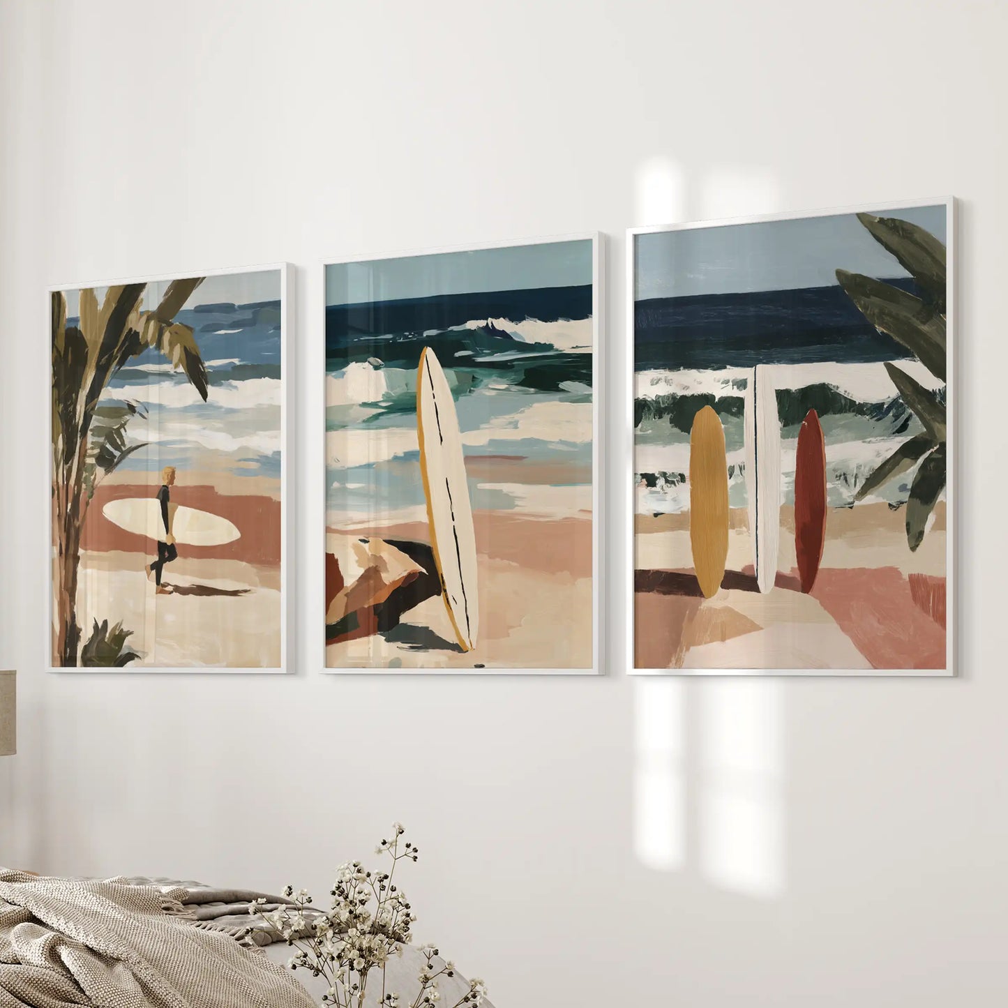 Three surfer-themed wall pieces in slim white frames line the wall beside the bed, adding silhouettes and coastal motion to the room.