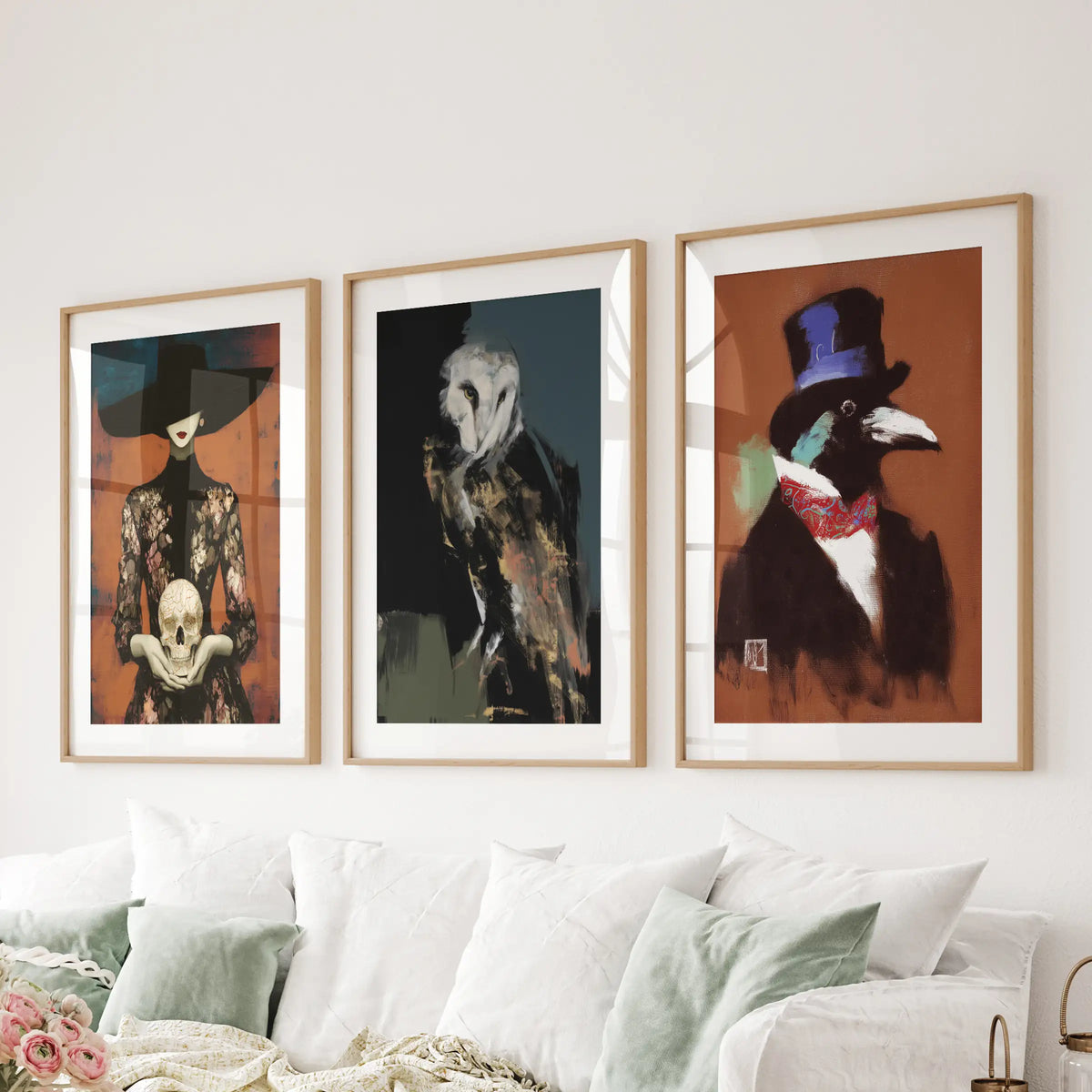 Set of three wall art prints featuring an owl, skull, and raven in matted thin wood frames, displayed over a living room couch.