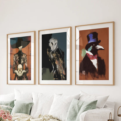 Set of three wall art prints featuring an owl, skull, and raven in matted thin wood frames, displayed over a living room couch.