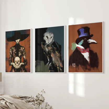 Owl, skull and raven three-piece wall art set in white frames, hung on the wall beside a bed in a bedroom.