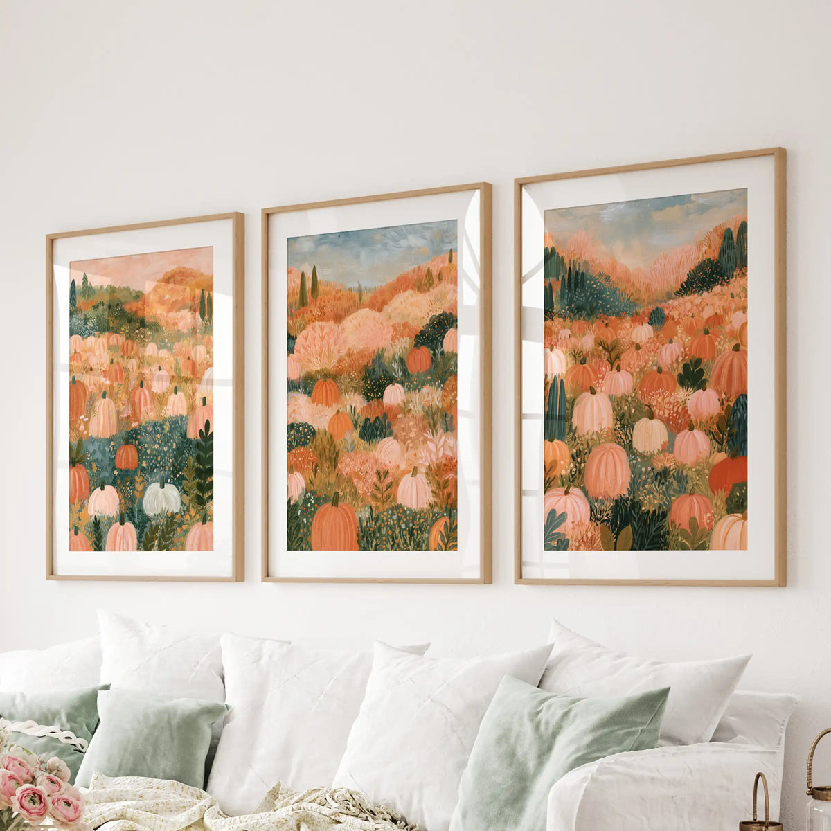 Three-panel wall art shows a cottagecore harvest scene in matted oak frames, spanning the sitting room above the sectional for a cozy vignette.