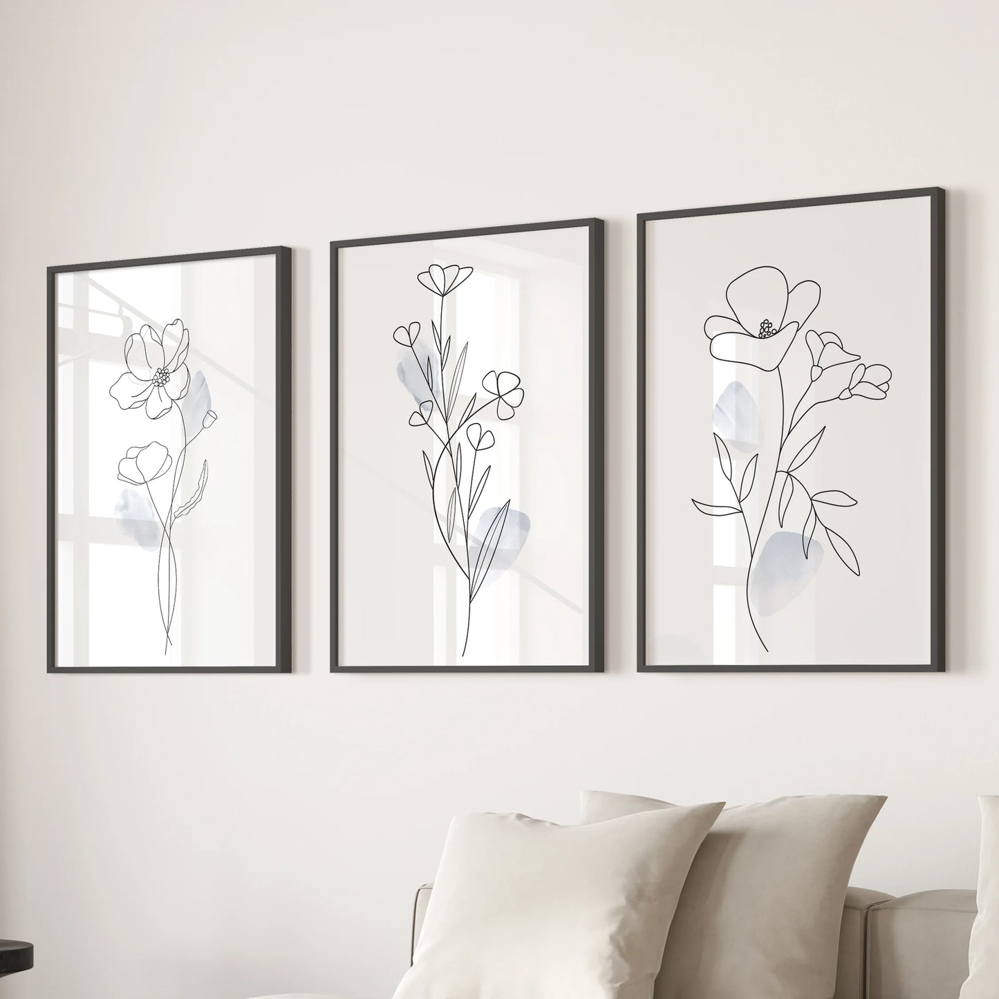 Three minimalist flower drawings in sleek black frames form wall prints that refresh the lounge when hung together over the couch.