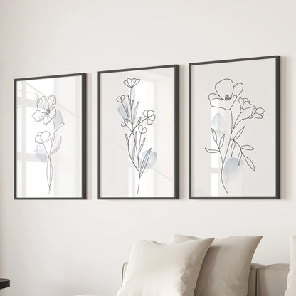 Three minimalist flower drawings in sleek black frames form wall prints that refresh the lounge when hung together over the couch.
