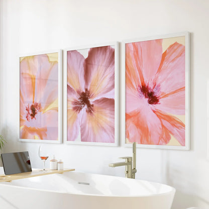 Pink abstract flower wall art in three white frames above a freestanding bathtub.