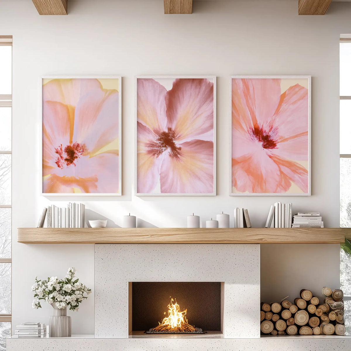 Abstract pink floral prints in white frames, a set of three above a fireplace.