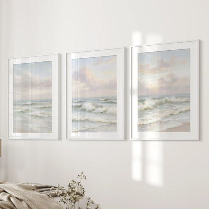 Three pastel-toned seascape prints in matted white frames bring gentle coastal light to the bedroom wall near the bed.