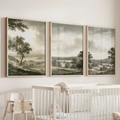 Pastoral countryside wall art in three wood-framed prints, displayed over a cot in a nursery room.