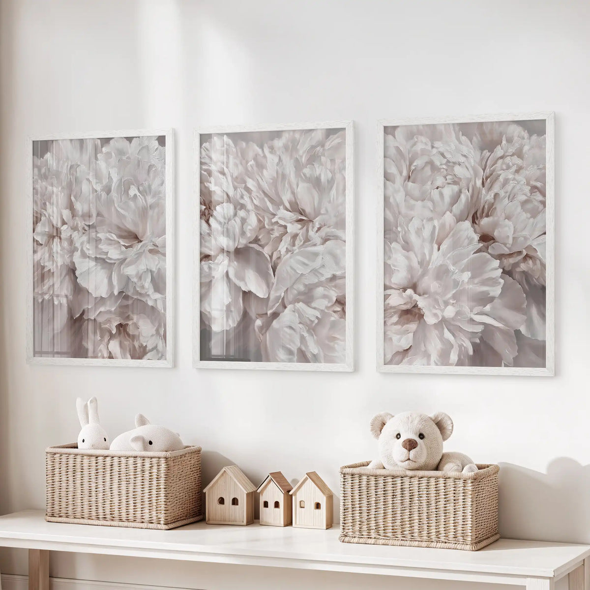 Pale peony petals fill three white-framed prints above baskets of toys, with taupe shadows adding depth between the overlapping layers.