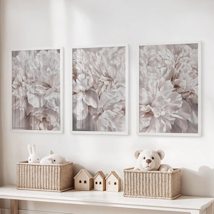Pale peony petals fill three white-framed prints above baskets of toys, with taupe shadows adding depth between the overlapping layers.