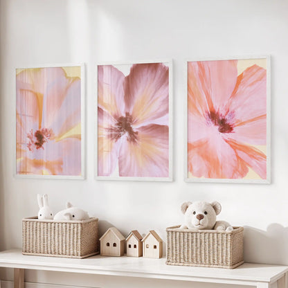 Broad pink petals and coral strokes fill three white-framed prints above a toy bench, with yellow highlights around the dark centers.