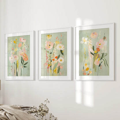 A 3-print set of delicate pink and green botanicals in white matted frames softens the bedroom wall near the bed.