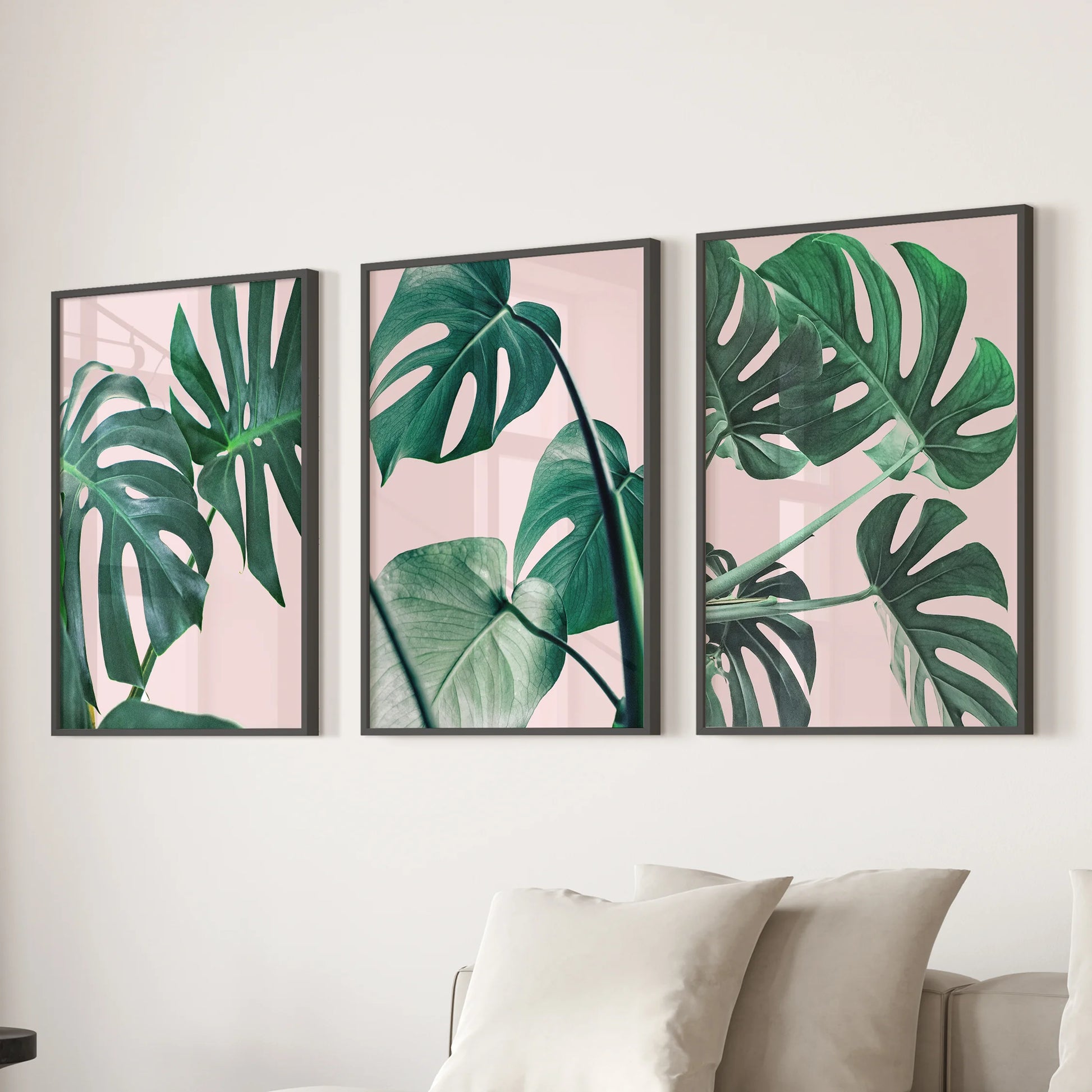 Three black-framed tropical prints of pink and green foliage style the wall over the sofa, giving the living room airy botanical charm.