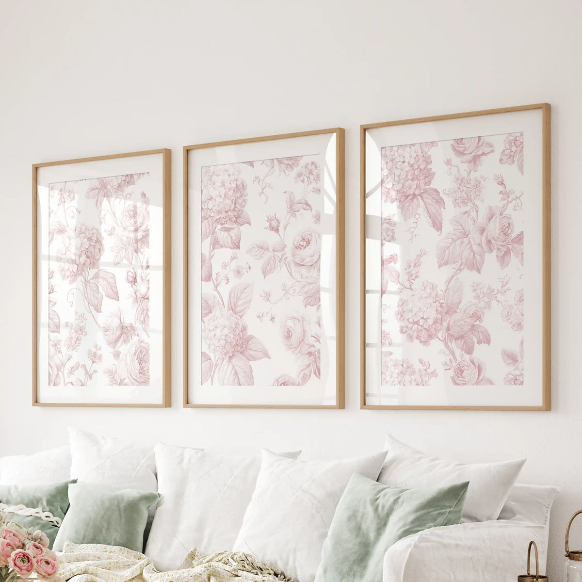 Pink rose and hydrangea prints hang in three matted oak frames above a sofa.