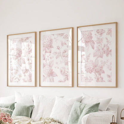 Pink rose and hydrangea prints hang in three matted oak frames above a sofa.