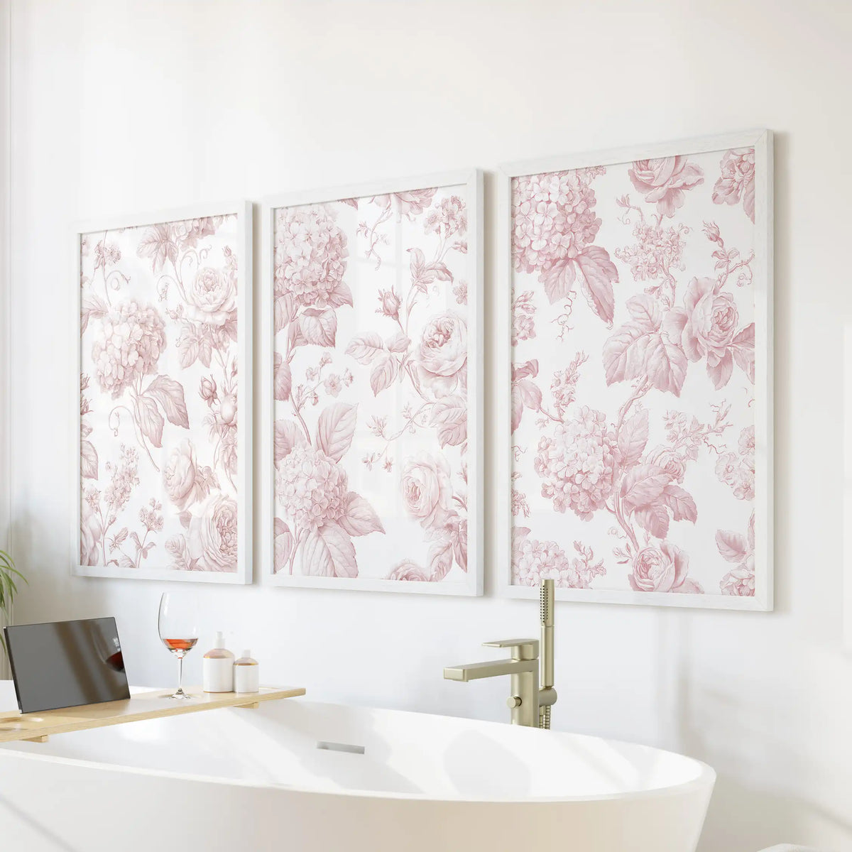 Blush floral pattern prints in white frames, a set of three above a freestanding bathtub.