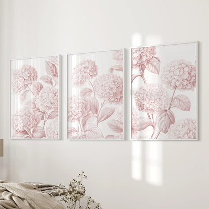 Pink hydrangea wall art in three white frames beside a bed.