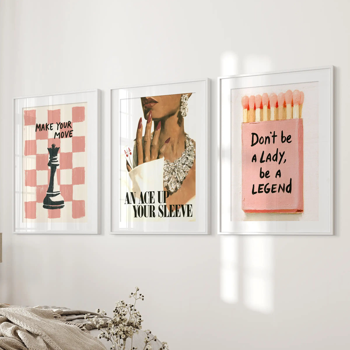 Pink glamour gallery wall set of three in white matted frames, displayed beside the bed in a bedroom.