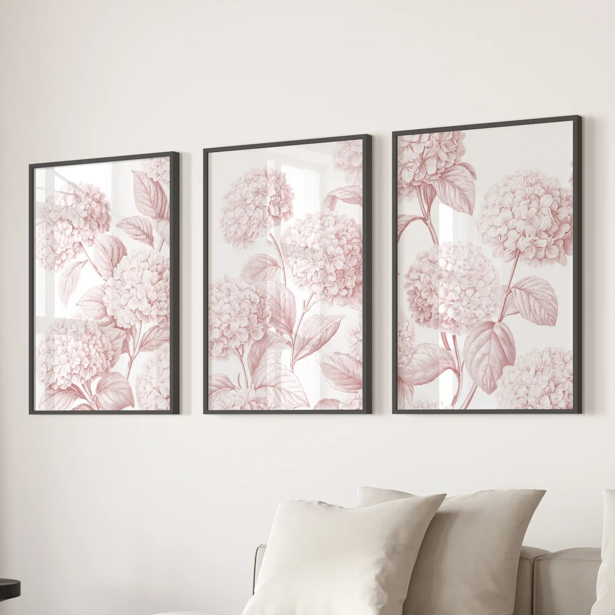 Three pink hydrangea pattern prints in black frames above a sofa.