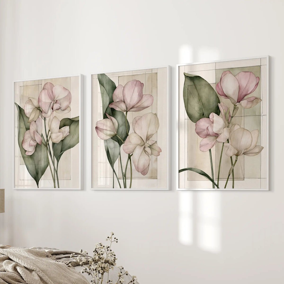 Fine outlines define the pink petals in three white-framed prints beside a bed, with long green leaves and faint rectangles on cream grounds.