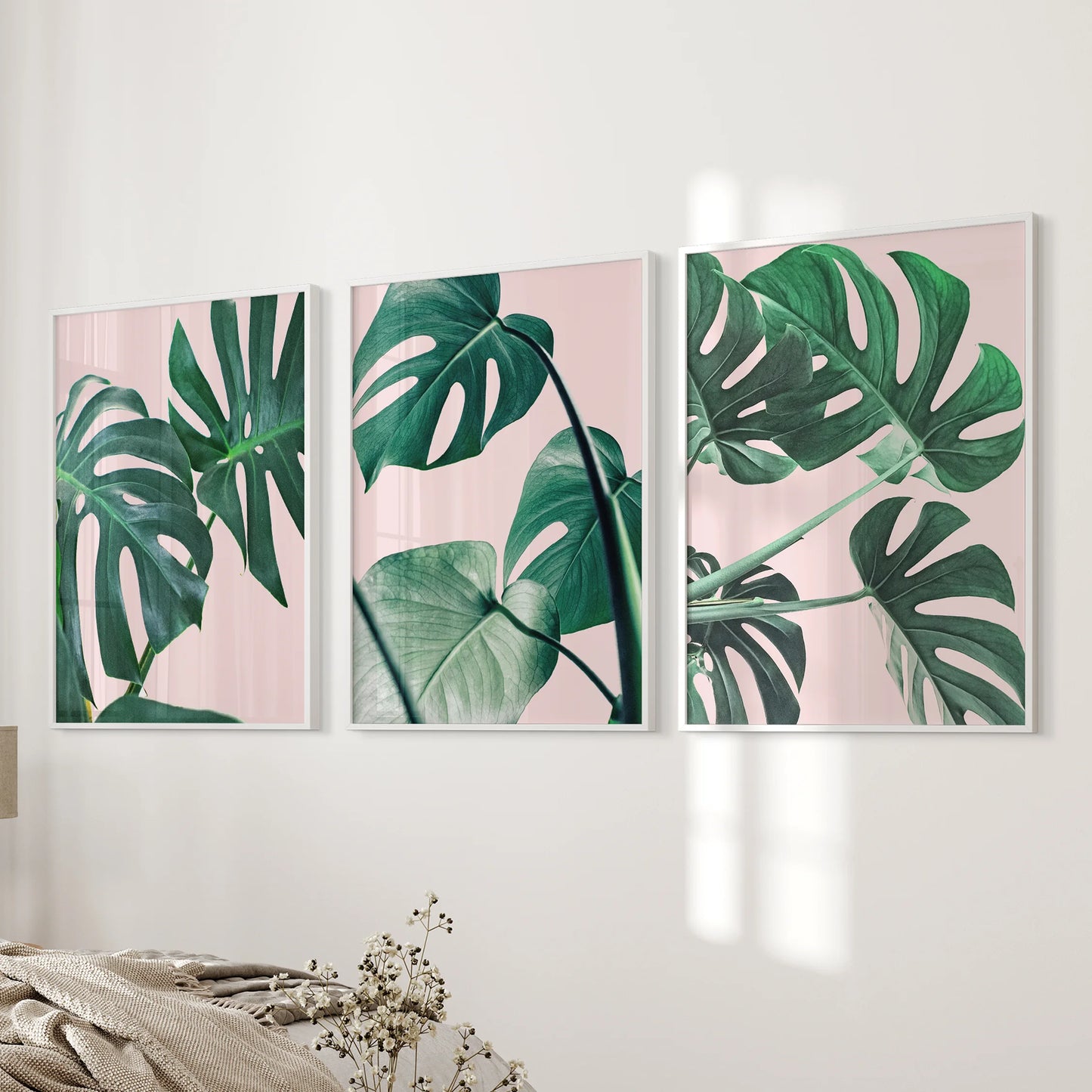 Tropical pink and green foliage 3-print set in white frames hangs beside the bed, delivering gentle botanical wall art that softens the bedroom.