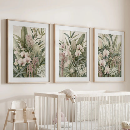 Above a white crib, oak frames with white mats surround three dense leaf compositions with pale orchids and trailing pink flowers.