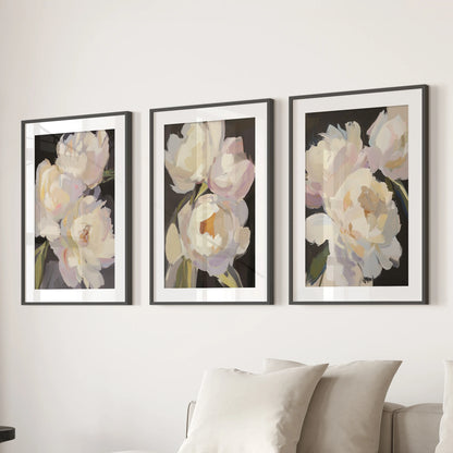 Three moody floral prints in black frames with white mats stretch behind the living room sofa, a refined wall art set with classic contrast.
