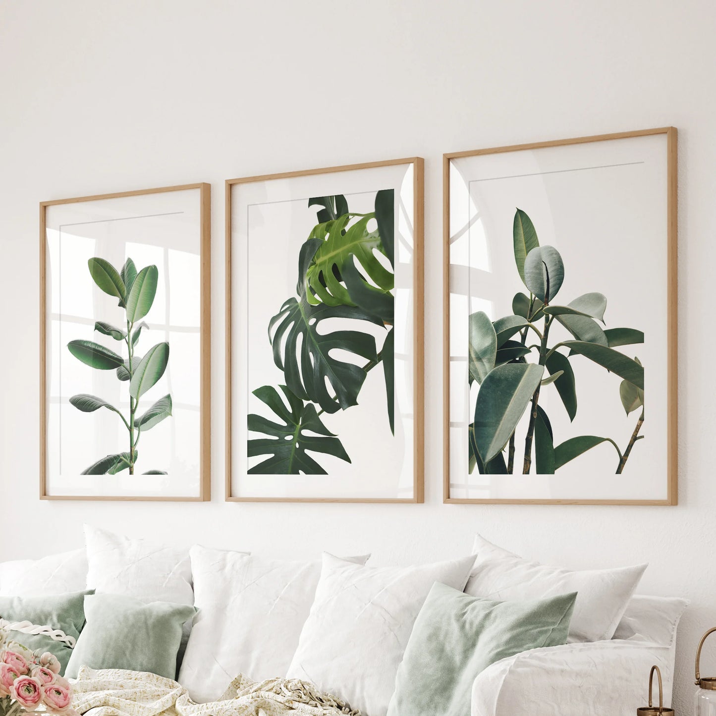 Tropical houseplants, wall art in three pieces with natural wood matted frames, creates a relaxed focal point in the family room, hovering over the couch.