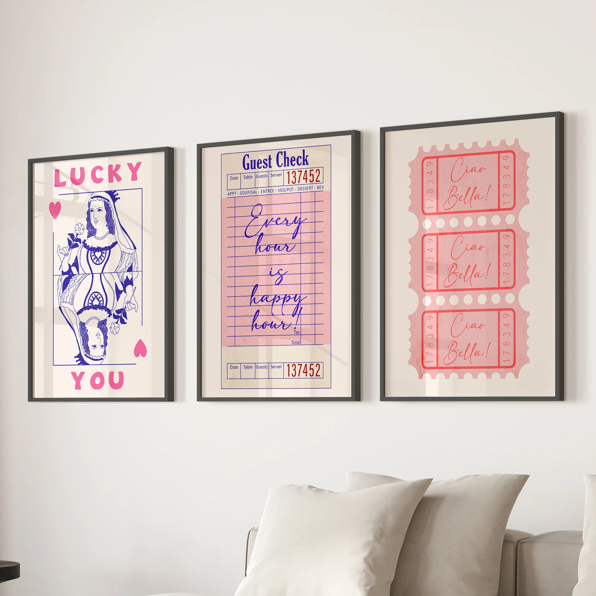 Three pink playing card prints framed in black create crisp wall decor above the living room couch, lending a polished, preppy vibe.