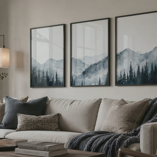 Misty mountain and pine forest triptych in black frames hang above a neutral living room sofa as the camera slowly moves closer