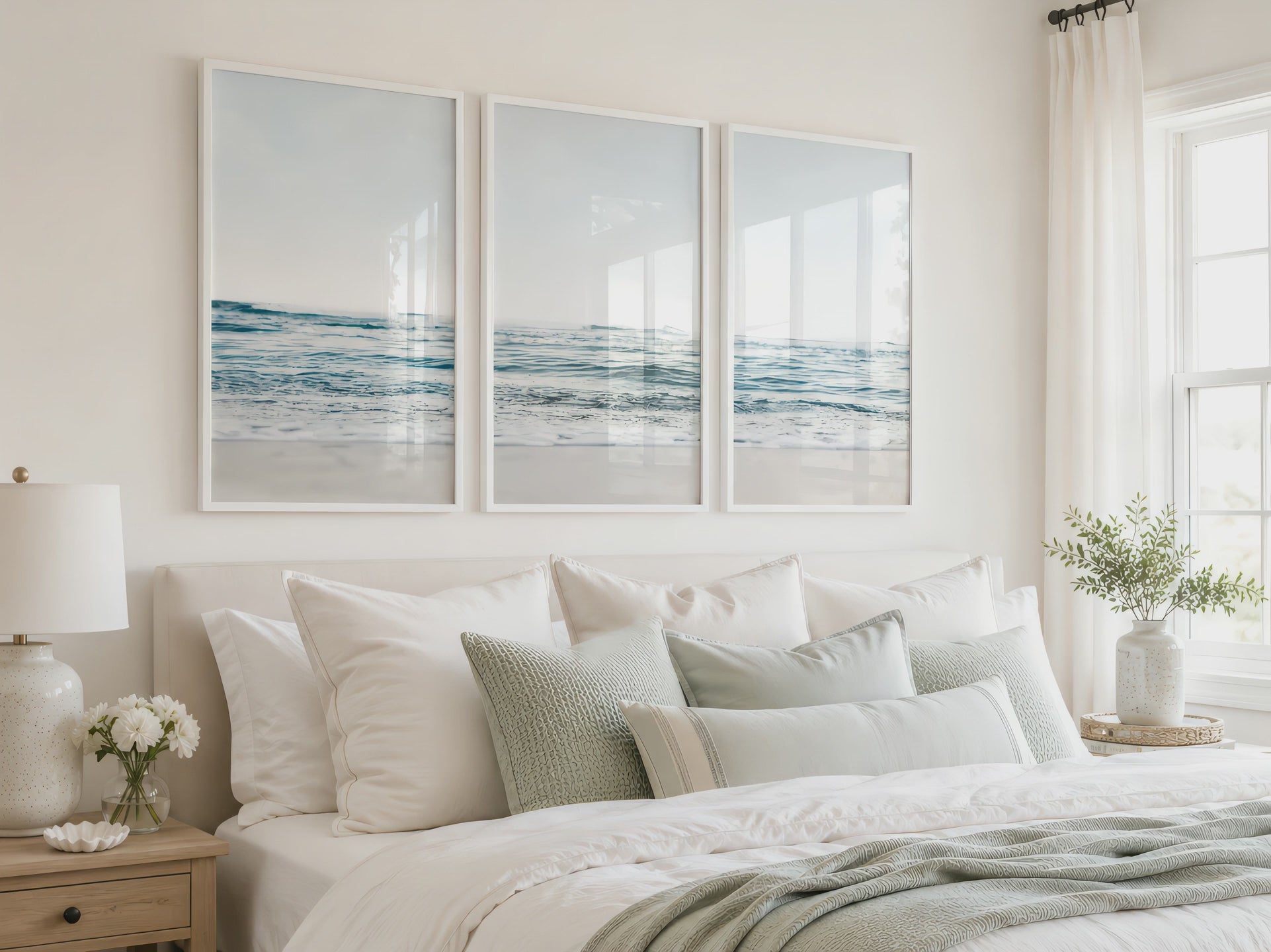 Three blue ocean prints in white frames hang above a bright neutral bed as the camera slowly moves closer