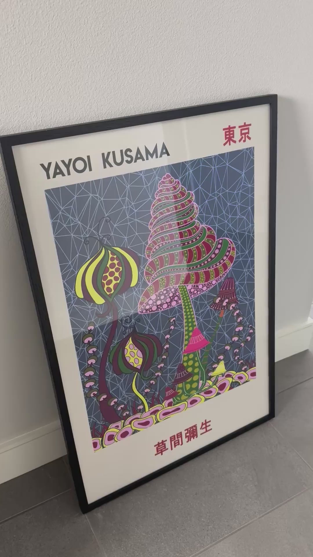 A framed Yayoi Kusama Japanese exhibition print is featured in a customer video review, showing the colorful artwork, black frame and hanging hardware.