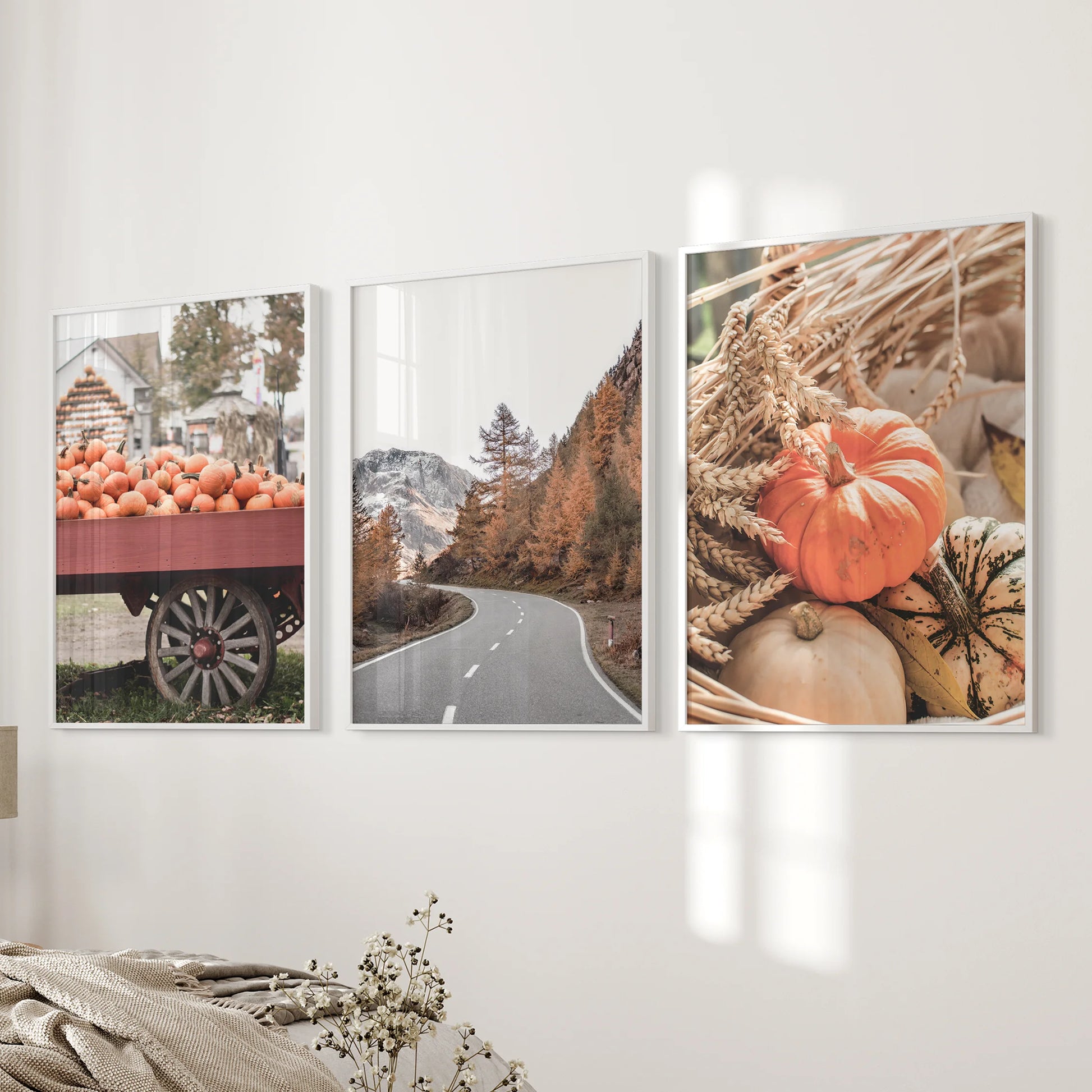 Three white-framed pumpkin patch art prints style the bedroom beside the bed, bringing a gentle harvest mood and cozy seasonal color.