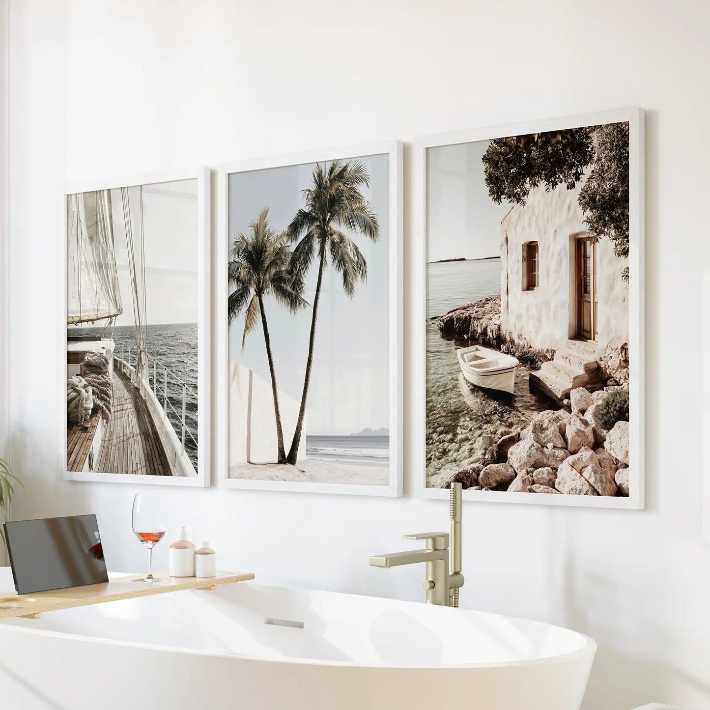 Sea photography wall art trio in white frames brings spa-like calm to the bathroom, hung above the bathtub with crisp, luminous blues.