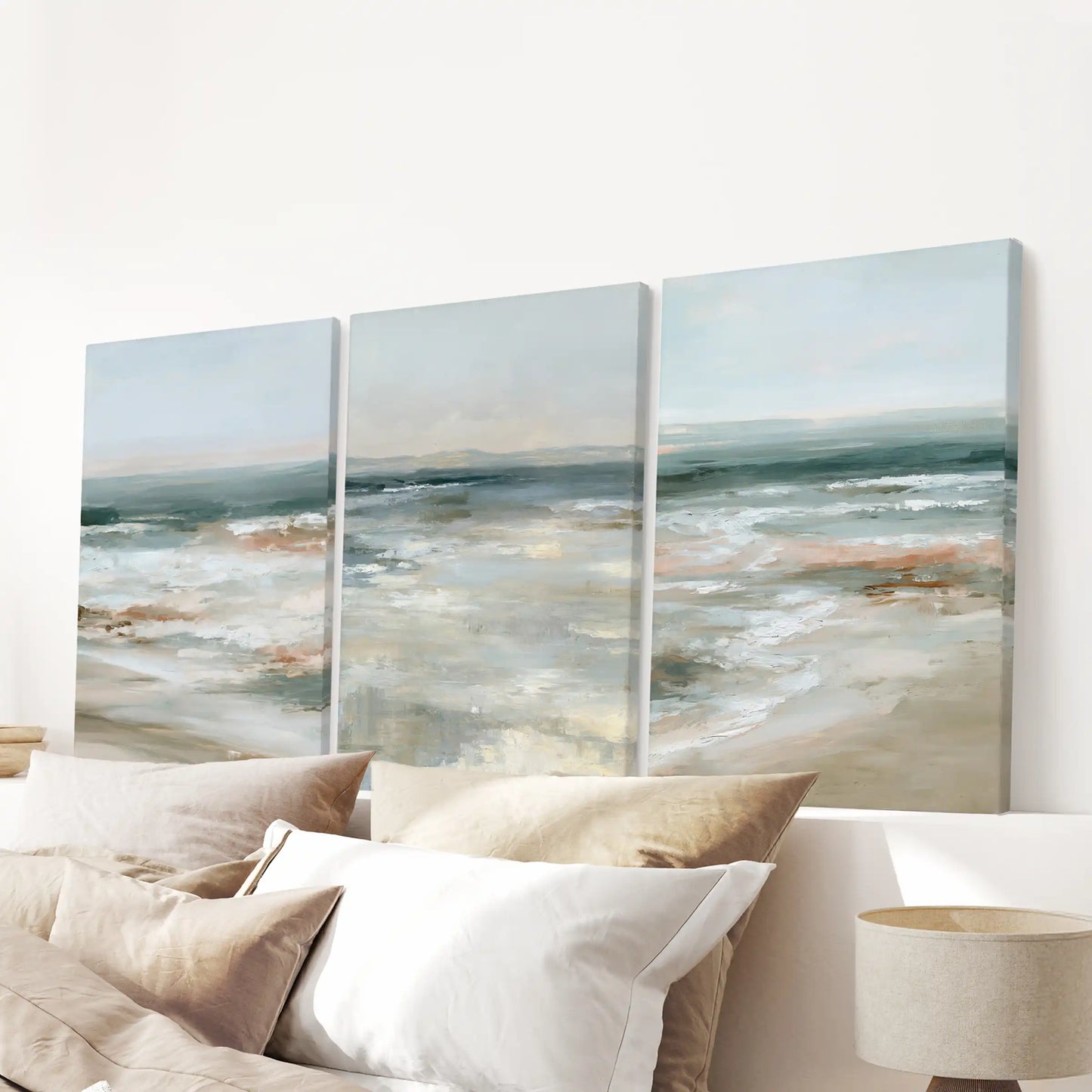 A three-panel shoreline gallery in wrapped canvas hangs above the bed, giving the bedroom soft coastal art and a quiet, luxurious hush.
