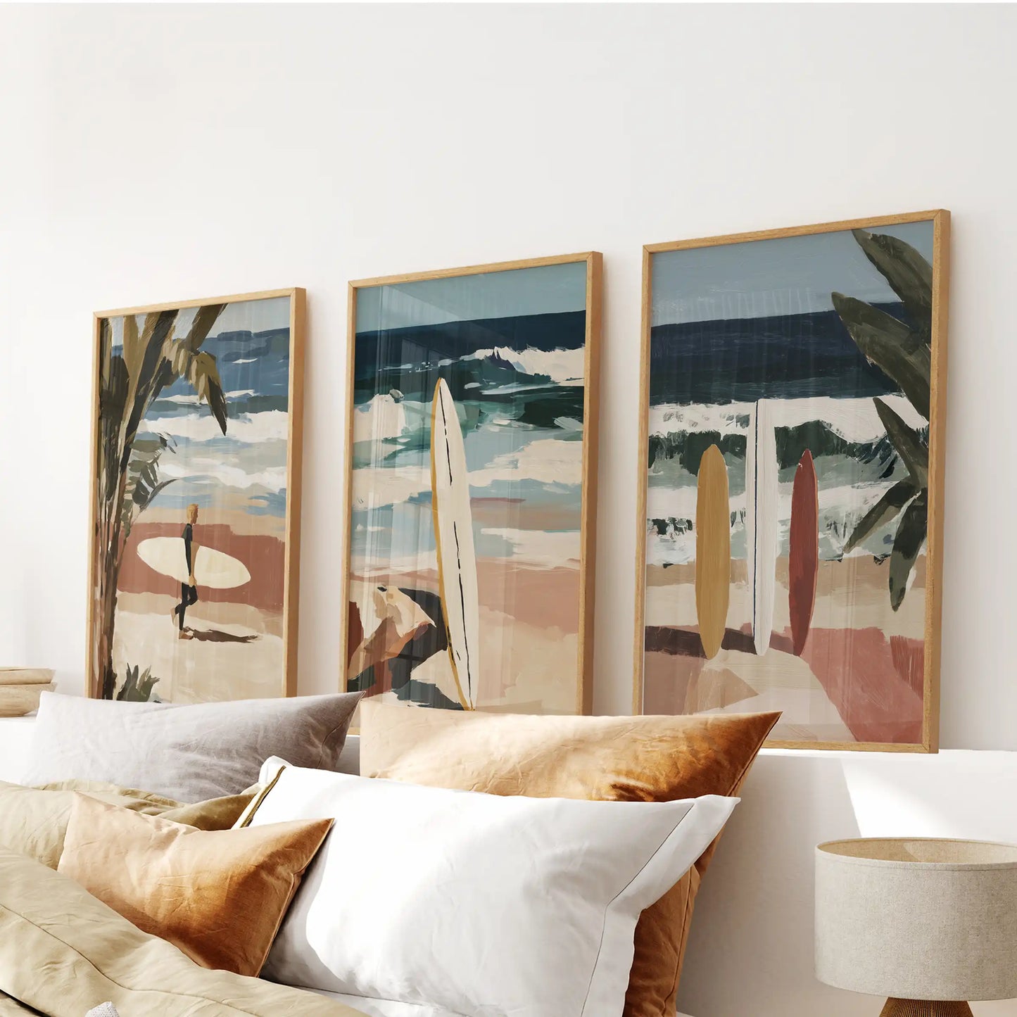 A three-poster coastal wall series in oak frames centers above the bed, pairing dune textures with airy pale sea tones.