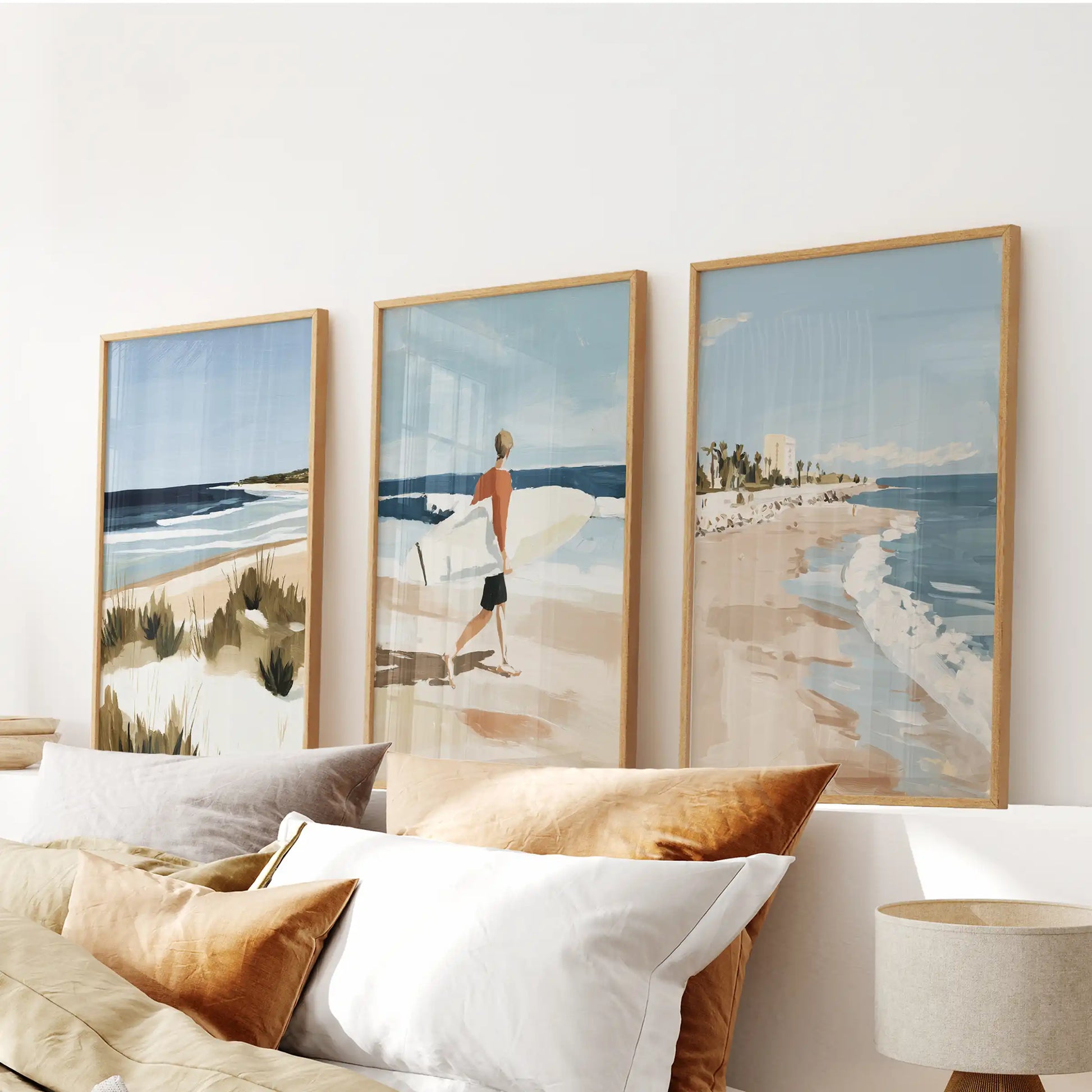Three natural-wood framed seaside prints sit above the headboard, bringing a soft hush of coastal calm into the bedroom.