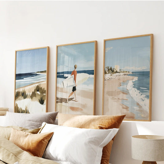 Three natural-wood framed seaside prints sit above the headboard, bringing a soft hush of coastal calm into the bedroom.