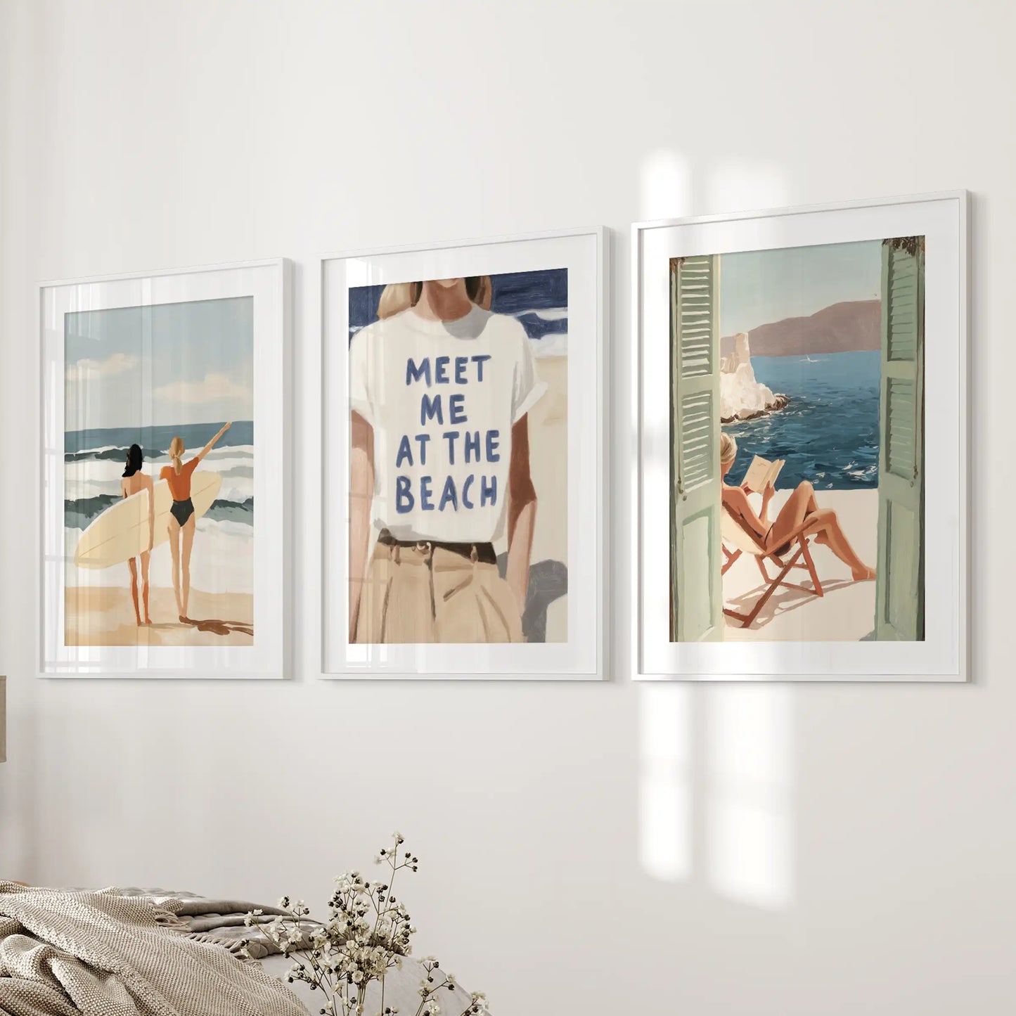Beside the bed, a softly matted trio of coastal wall decor prints in white frames brings serene shoreline quiet to the bedroom space.