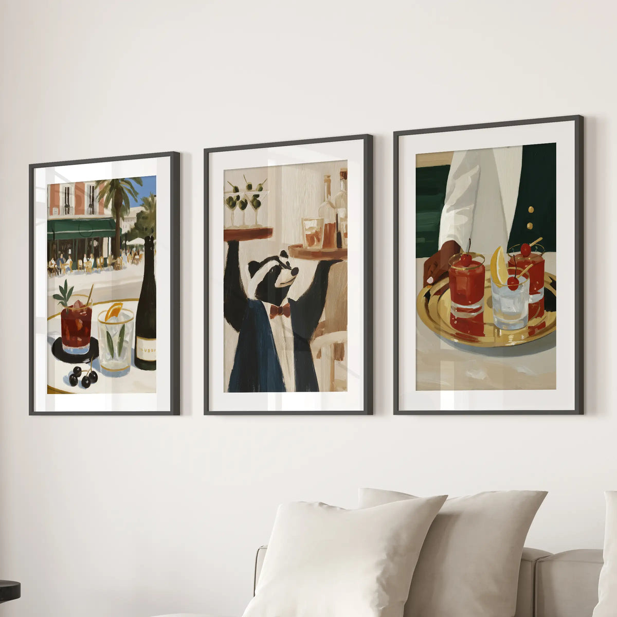 Set of three wall art prints with retro drink illustrations, displayed in black matted frames above a living room sofa.