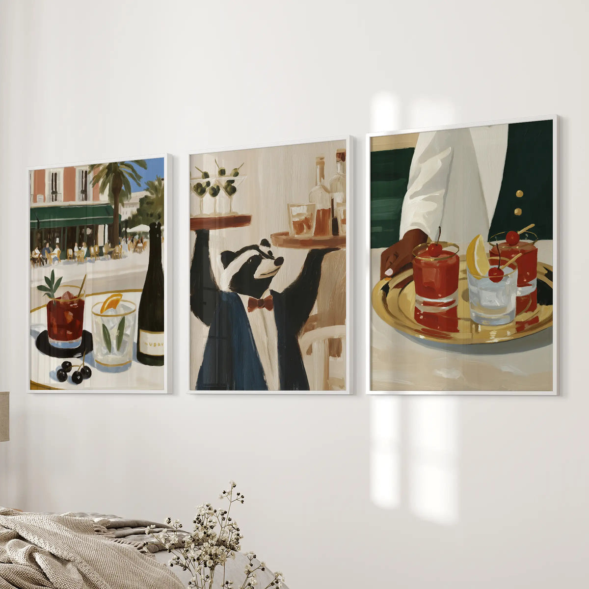 Wall art trio featuring retro drink illustrations, shown in white frames beside a bedroom bed.