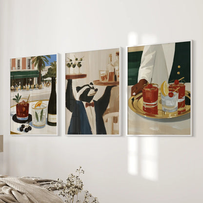 Wall art trio featuring retro drink illustrations, shown in white frames beside a bedroom bed.