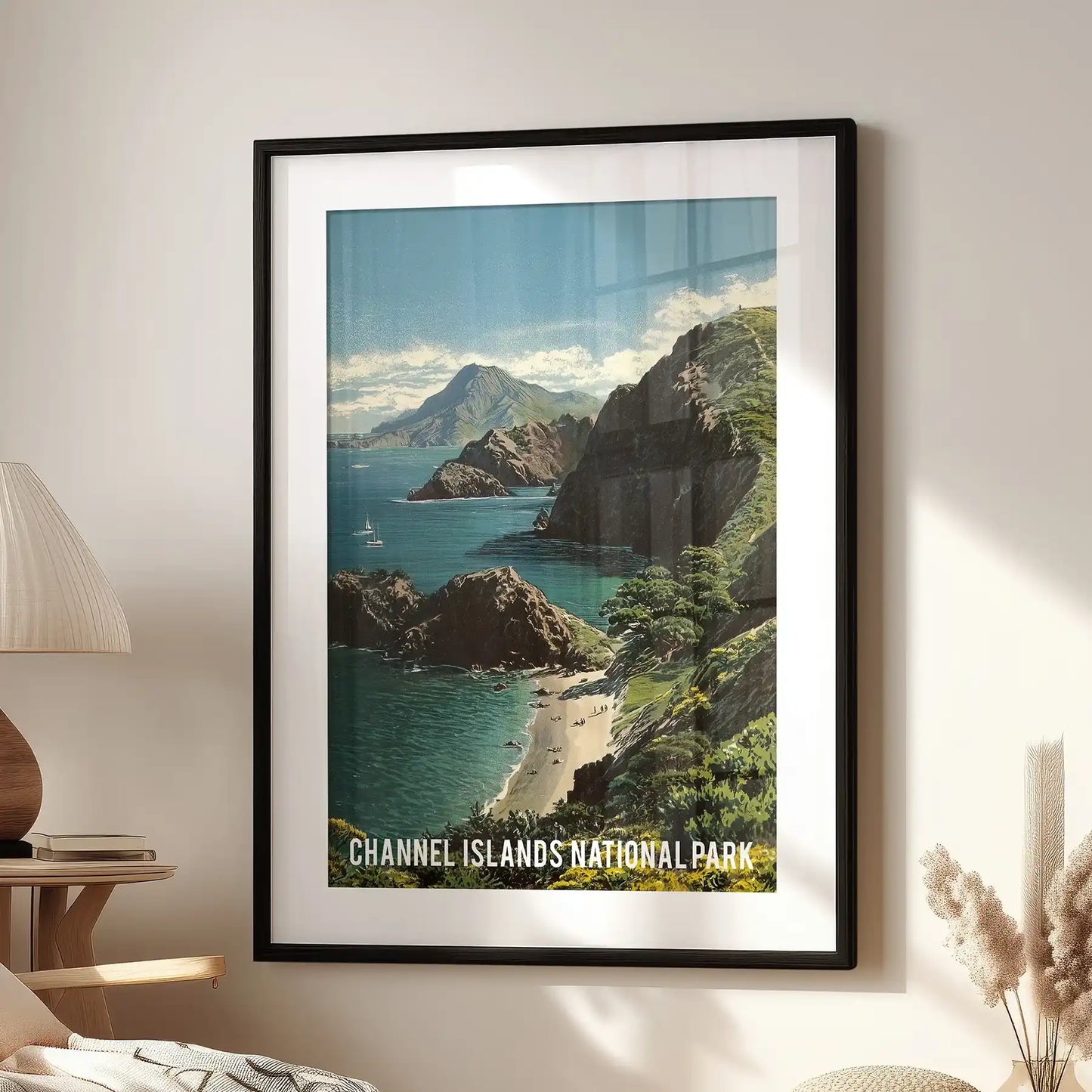California coastal cliffs single wall art piece in a black frame with white mat, placed above a lounge chair in the sitting room, echoing vintage park poster style.