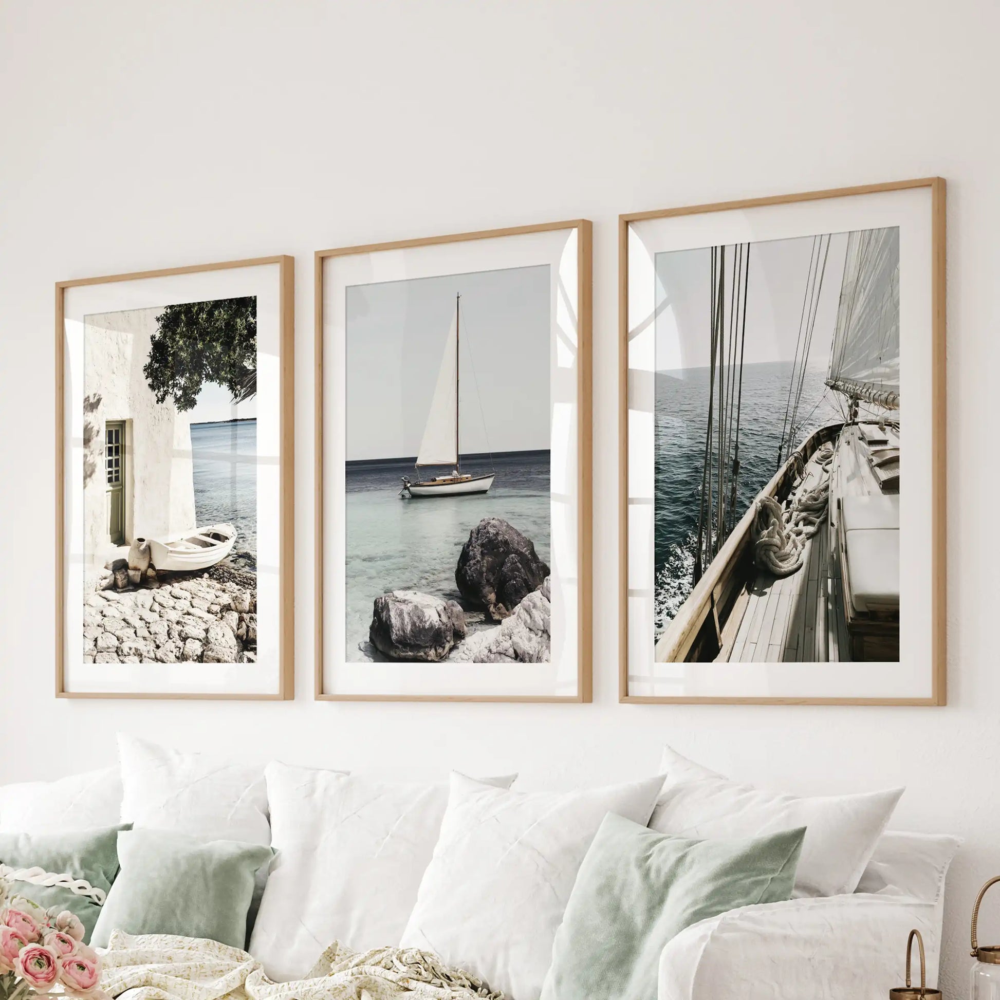 Sailboat photo art, wood-framed with mats, sets the tone in the sitting room; the set of 3 art prints hangs behind the couch for an airy, nautical statement.